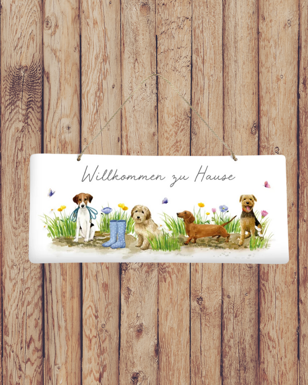 Fröhliches Metallschild ‚Hundespaß‘ vom Grätz Verlag vor Holzwand dekoriert, mit Hunden, Blumen und Schmetterlingen als Willkommensgruß.