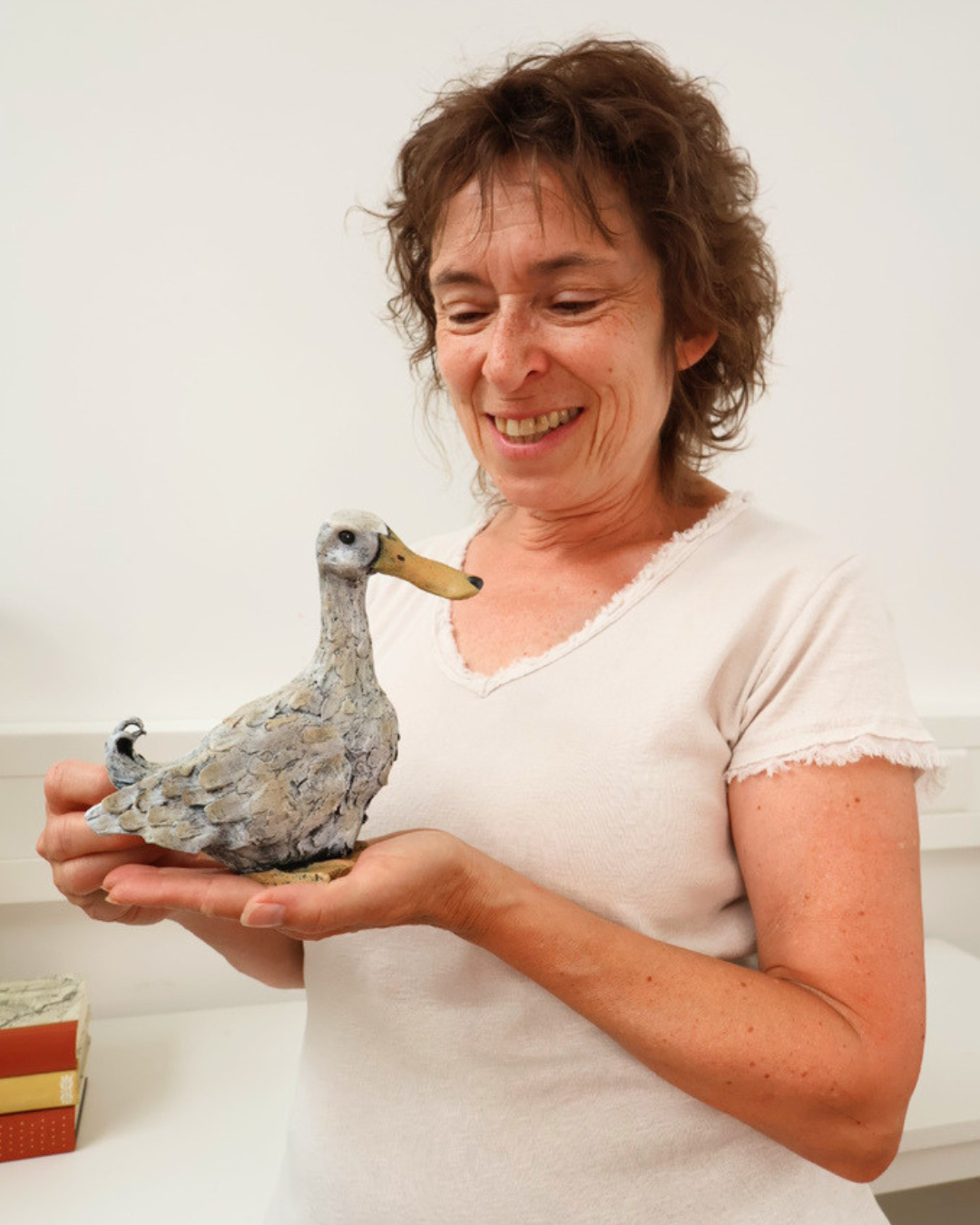 Zu sehen ist wie eine Frau die Enten Figur "Lily" von Wrendale Designs in der Hand hält. Die Ente schaut nach rechts und Die Frau auf die Ente.