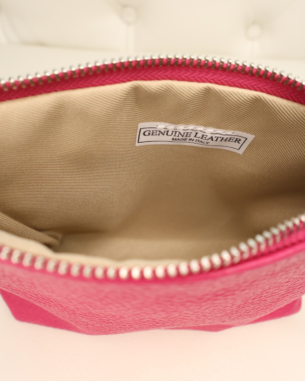 Innenansicht der Leder Kosmetiktasche "Ella" in dunkel pink von Südstrand. Zu sehen ist eine Innenseite mit Stoff und ein kleines Etikett mit der Schrift "Genuine Leather made in Italy".