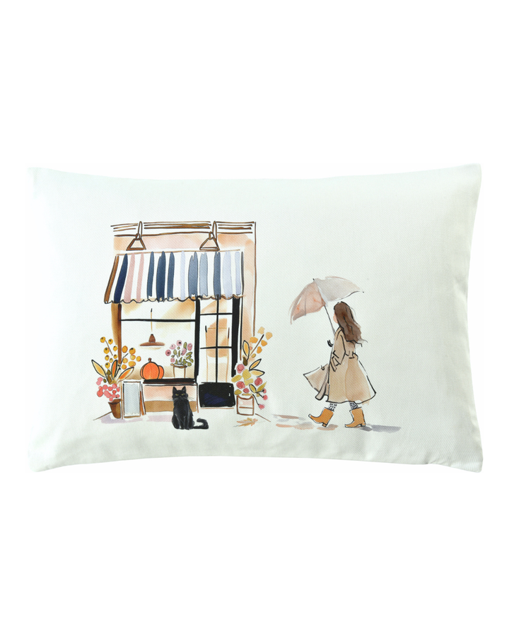 Herbstlicher Kissenbezug "Le Chat" von Sander Table + Home in Aquarelloptik mit Katze vor Cafe und Frau mit Schirm.