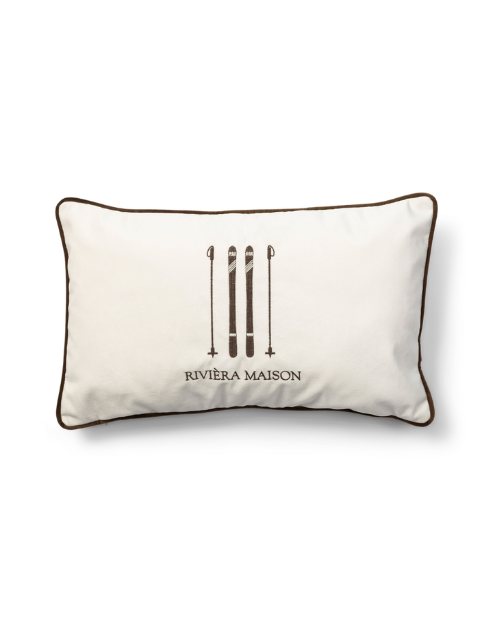 Kissenbezug RM Ski Club Pillow Cover von Rivièra Maison mit gestickten Ski auf hellem Stoff vor weißem Hintergrund.