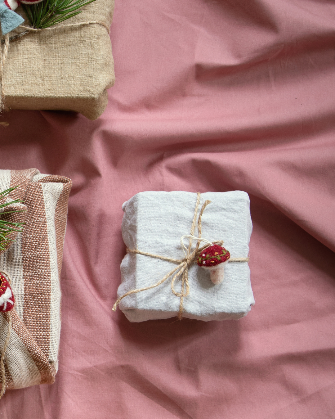 Kleiner bestickter Filzpilz von Gry & Sif als Geschenkanhänger an weißem Päckchen.