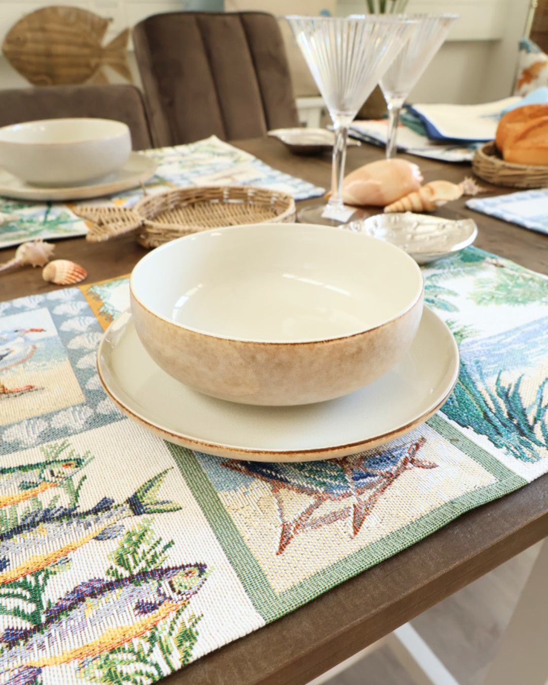 Weiße Schüssel und Teller von Riviera Maison auf einem maritimen "Costa" Platzset von Sander. Die Produkte liegen auf einem maritim dekorierten Tisch.