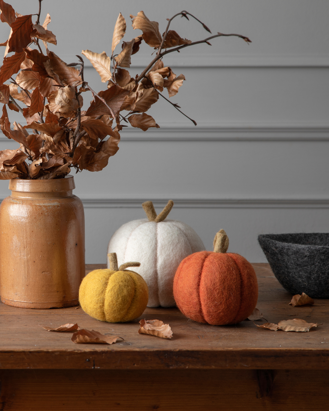 Drei verschiedene Deko-Kürbisse in helb, orange und weiß von Gry & Sif sind miteinander auf einem herbstlichen Holztisch miteinander kombiniert.