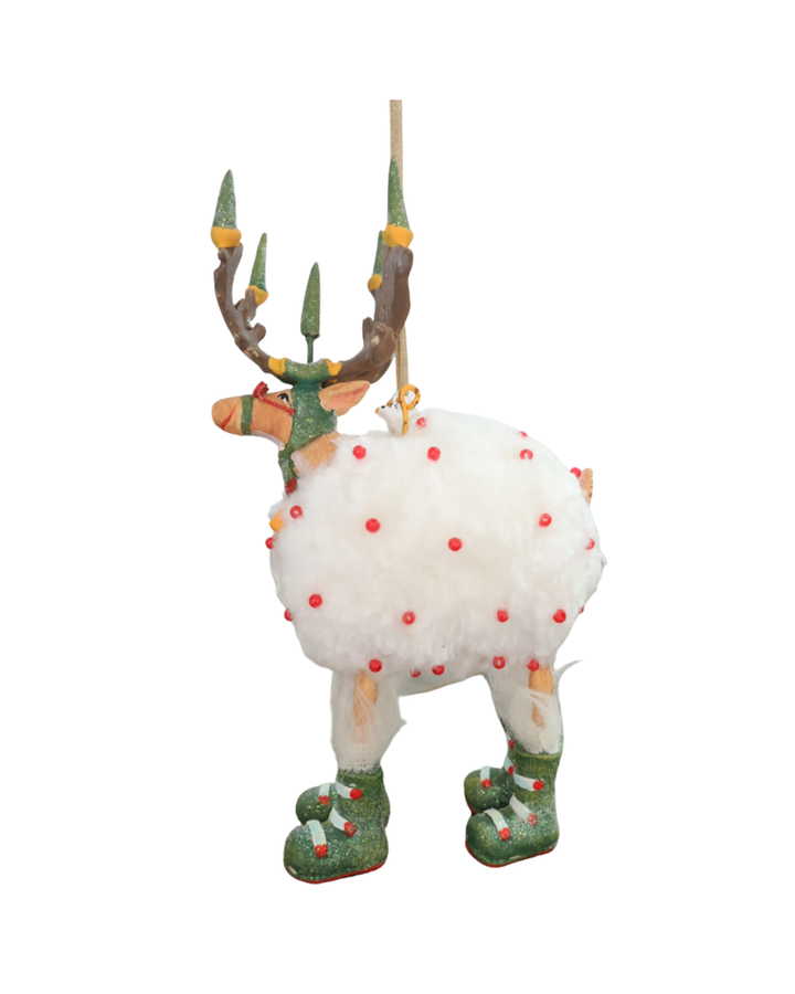 "Dash Away Blitzen Rentier" Krinkle von Patience Brewster vor weißen Hintergrund. Zu sehen ist ein Rentier mit rot bepunkteten Schafsfell vor weißen Hintergrund. Daas Rentier hat viele grüne und rote Details.