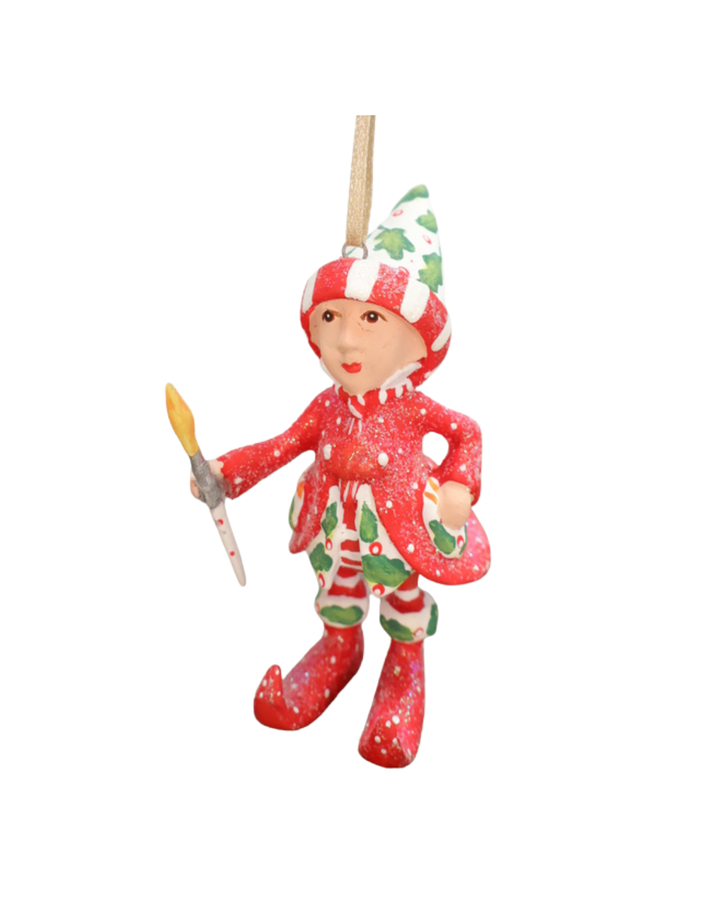 Mini "Vixens Elf" Krinkle vor weißen Hintergrund. Zu sehen ist ein größtenteils rot bekleideter Elf mit weißen Pünktchen, pflanzlichen Details und einem kleinen Pinsel in der Hand. 