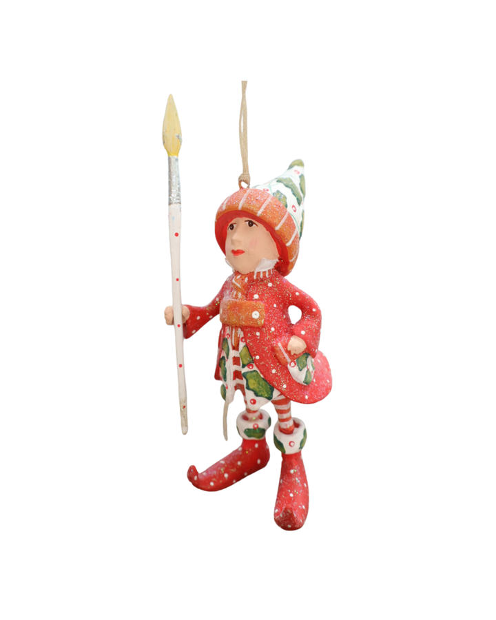  "Vixens Elf" Krinkle vor weißen Hintergrund. Zu sehen ist ein größtenteils rot bekleideter Elf mit weißen Pünktchen, pflanzlichen Details und einem großen Pinsel in der Hand. 