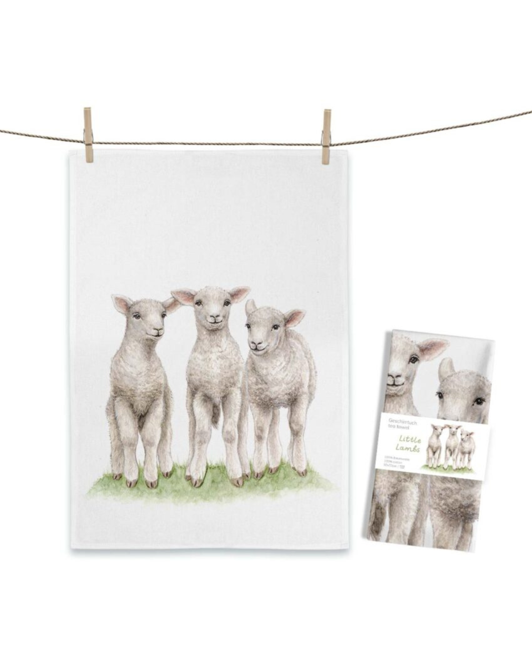Lämmer Geschirrtuch Little Lambs von Maluu mit drei illustrierten Lämmern auf Wiese auf hellem Tuch an einer Leine aufgehängt