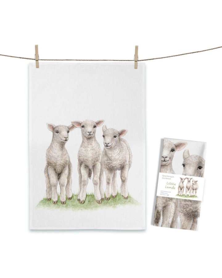 Lämmer Geschirrtuch Little Lambs von Maluu mit drei illustrierten Lämmern auf Wiese auf hellem Tuch an einer Leine aufgehängt