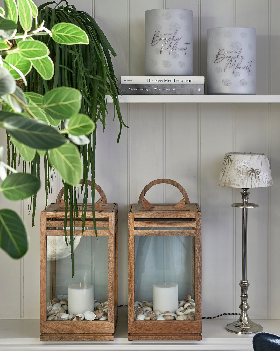 Schlanker Lampenfuß L'Hotel Lampbase von Rivièra Maison mit hellem Lampenschirm, kombiniert mit zwei Holzlaternen auf Regal in heller Wohnszene.