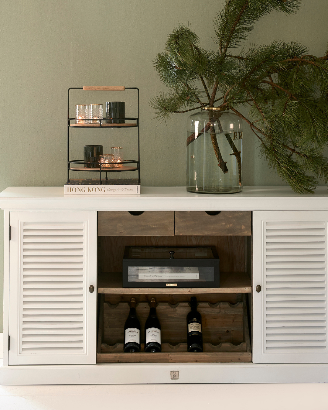 Eine Lower East Side Etagere ist in einem Wohnzimmer auf einem weißen Sideboard von Rivièra Maison dekoriert.