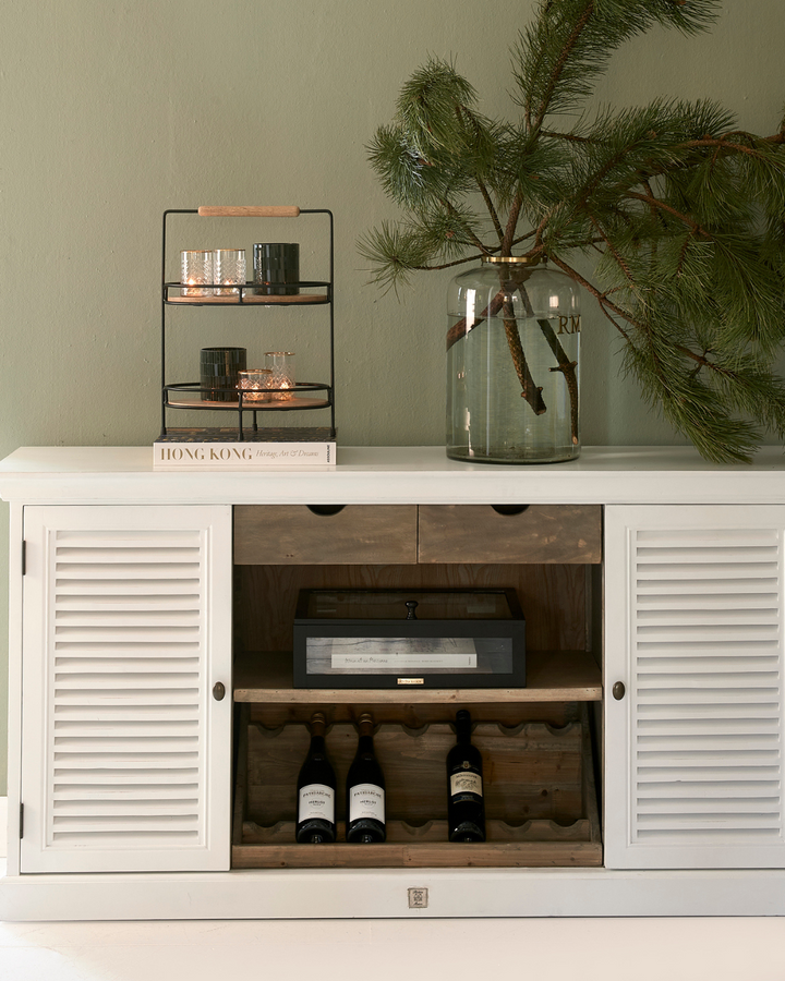 Eine Lower East Side Etagere ist in einem Wohnzimmer auf einem weißen Sideboard von Rivièra Maison dekoriert.