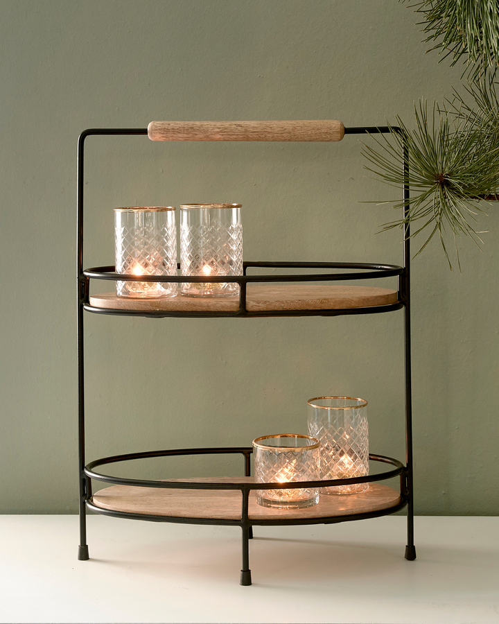 Die Lower East Side Etagere von Rivièra Maison ist mit vier Glas Windlichtern auf einer weißen Kommode vor einer mintgrüner Wand dekoriert.