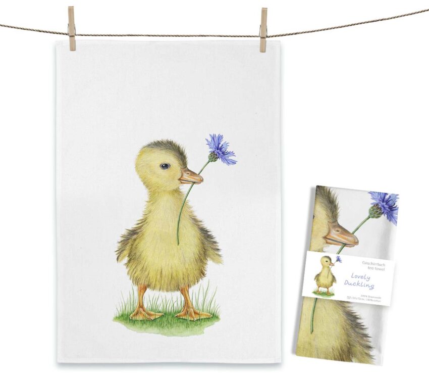 Entenküken Geschirrtuch Lovely Duckling von Maluu mit gelbem Küken und blauer Blume auf weißem Küchentuch vor neutralem Hintergrund