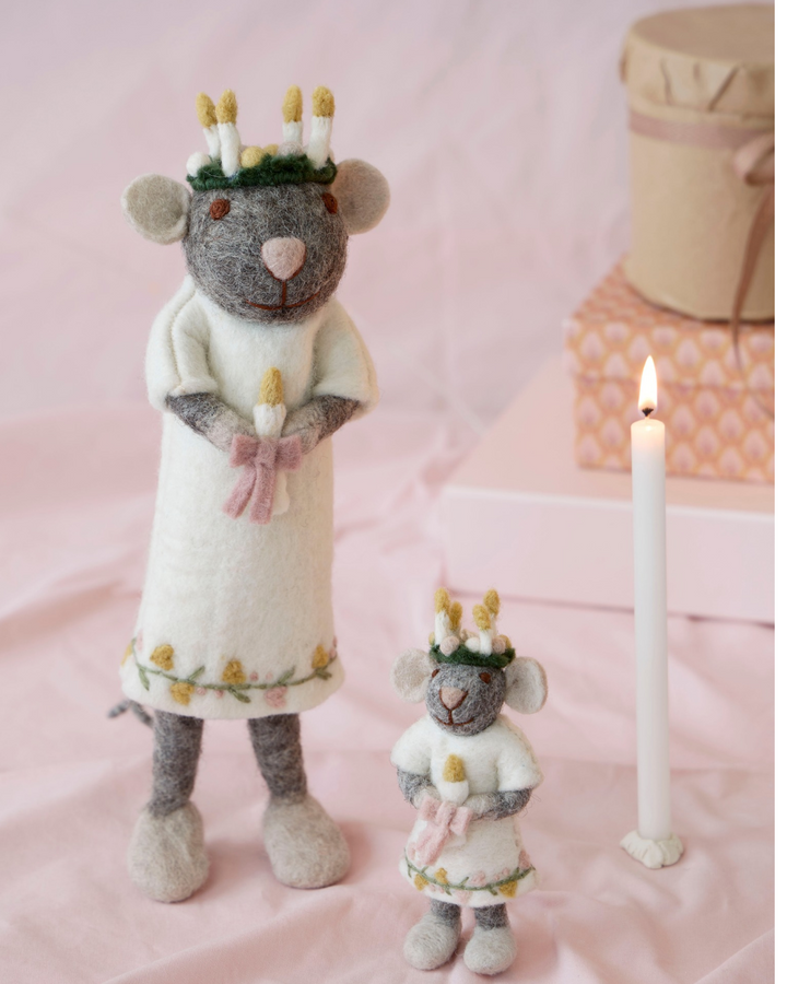 Heilige Mäuse Mädchen "Lucia" von Gry & Sif dekoriert. Zu sehen sind 2 graue Mäuse eine größere und eine kleinere mit einem weißen Oberteil und einer pinken schleife mit einer Kerze in den Händen. Sie tragen ein Kranz mit vielen Kerzen auf dem Kopf.  Im Hintergrund ist eine Kerze und Geschenkverpackungen zu sehen.