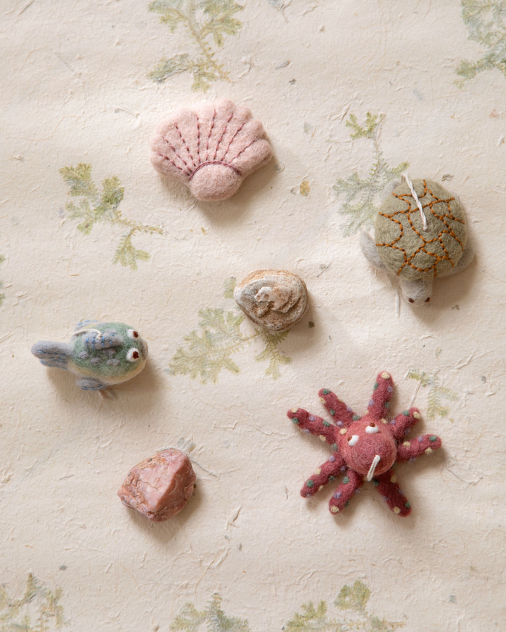 Mehrere maritime Filzanhänger von Gry & Sif mit Kugelfisch, Muschel, Schildkröte und Seestern dekorativ auf heller Fläche ausgelegt