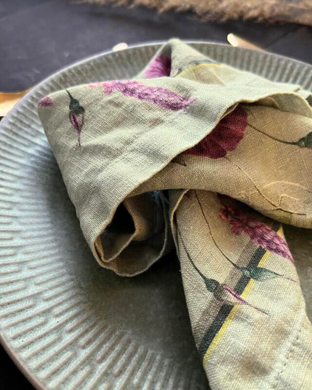 Detailansicht des Blumenmusters der Leinenserviette Blossom Garden von Koustrup & Co. auf dunklem Grund.