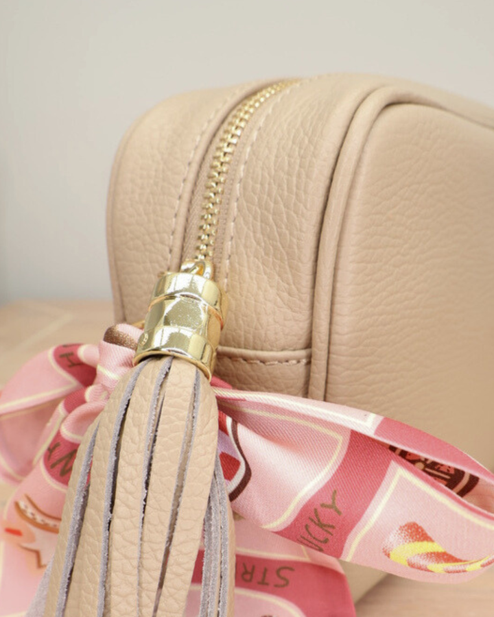 Nahaufnahme des Reißverschlusses der Cappuccino Lederhandtasche „Isolde“ mit Bandana-Anhänger und goldenen Details.