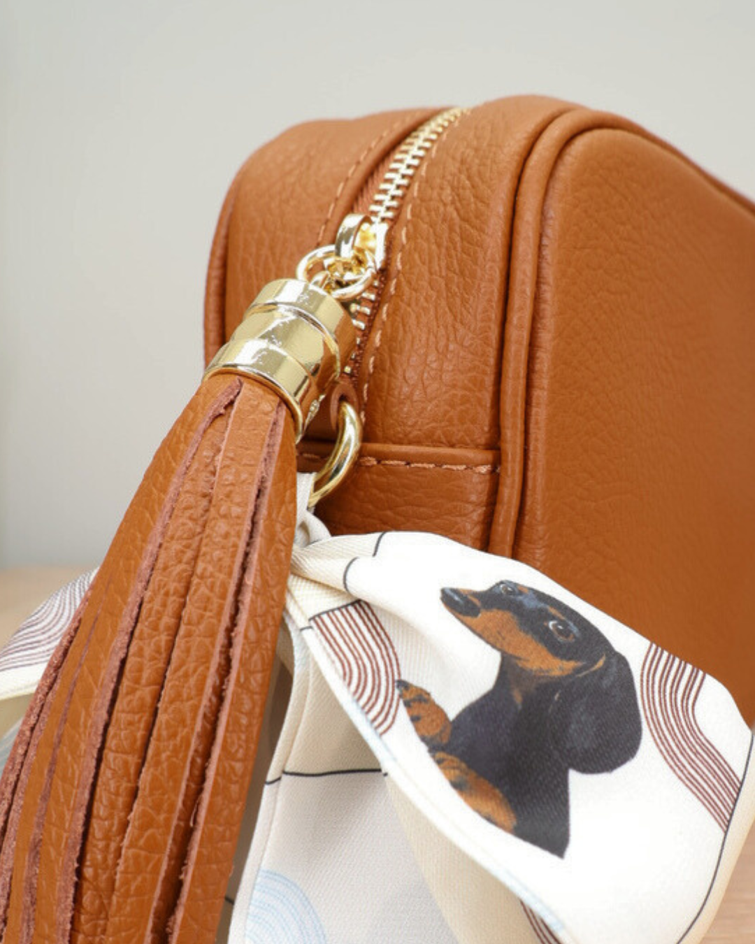 Nahaufnahme des Reißverschlusses der schokoladen Lederhandtasche „Isolde“ mit Dackel Bandana-Anhänger und goldfarbenem Metallverschluss.