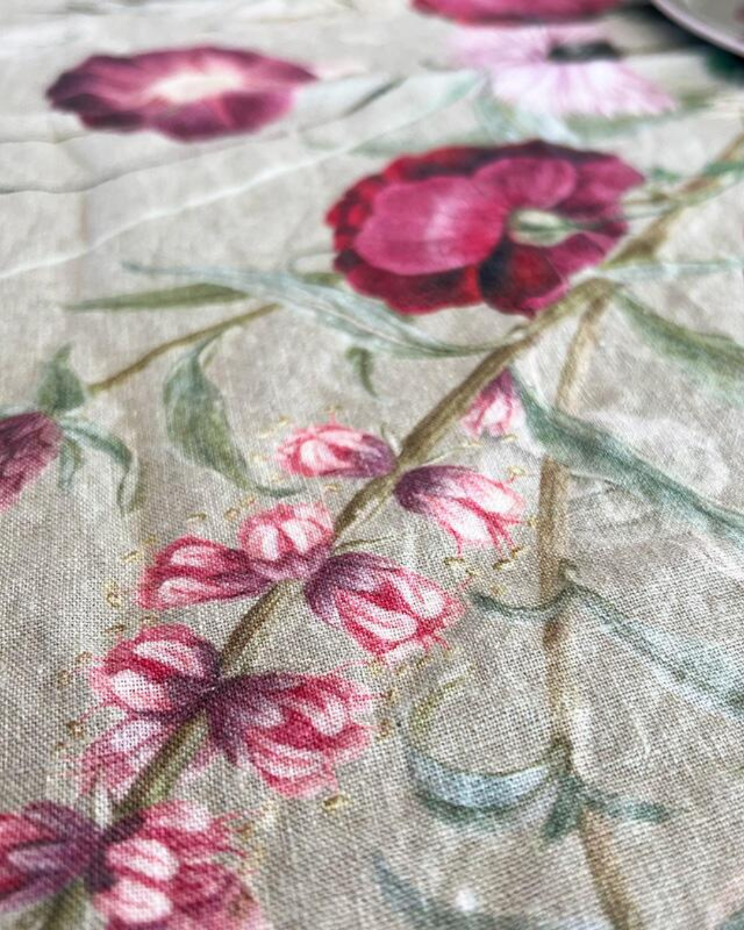 Nahaufnahme der Blumenmuster auf dem Leinen-Tischläufer "Blossom Garden". Die natürliche, leicht strukturierte Oberfläche des Leinens ist charakteristisch.