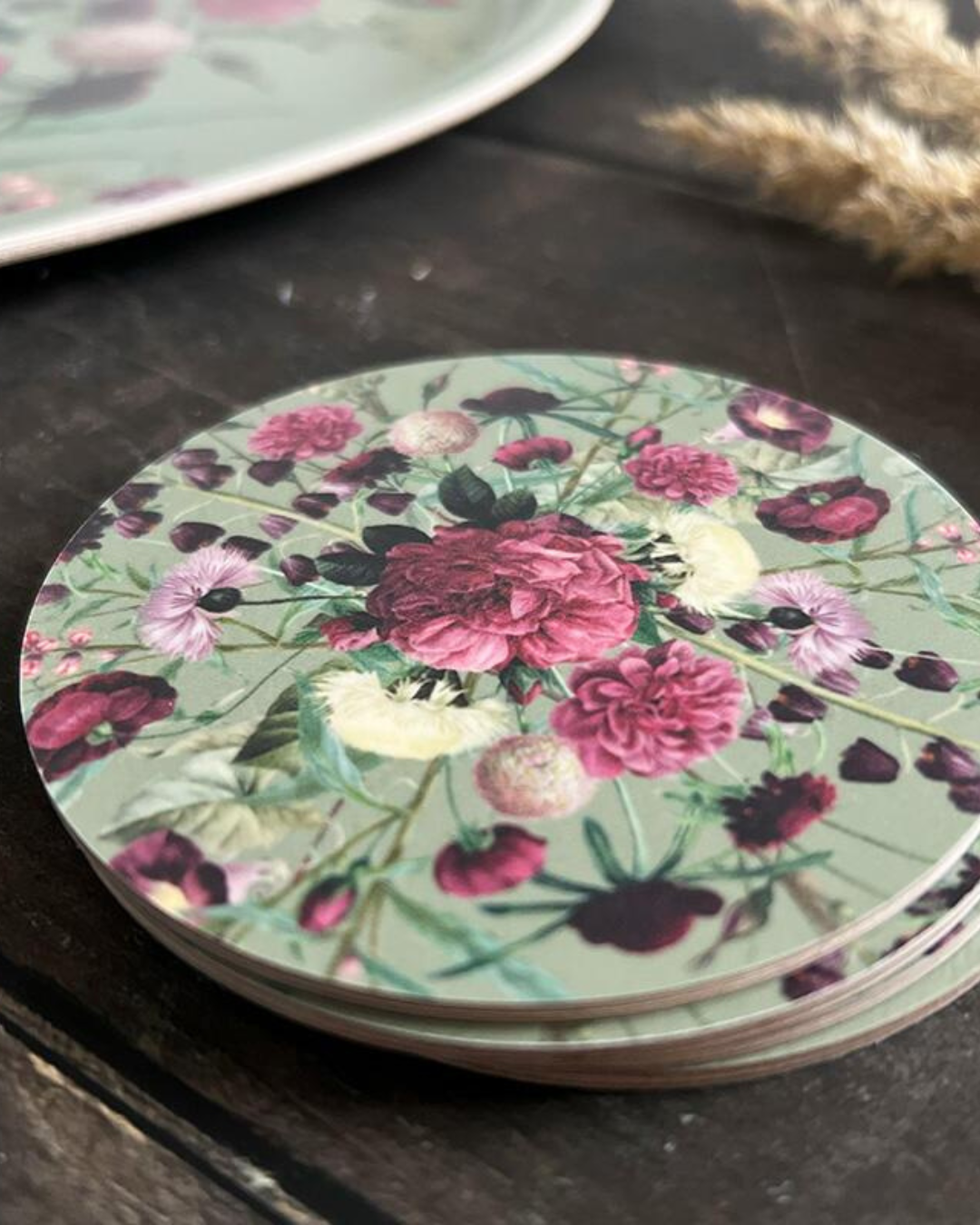 Nahaufnahme der Untersetzer "Blossom Garden" mit farbenfrohen Blumenmotiv im 4er Set aufeinander gestapelt. Die Untersetzer liegen auf einem dunklen Holztisch.