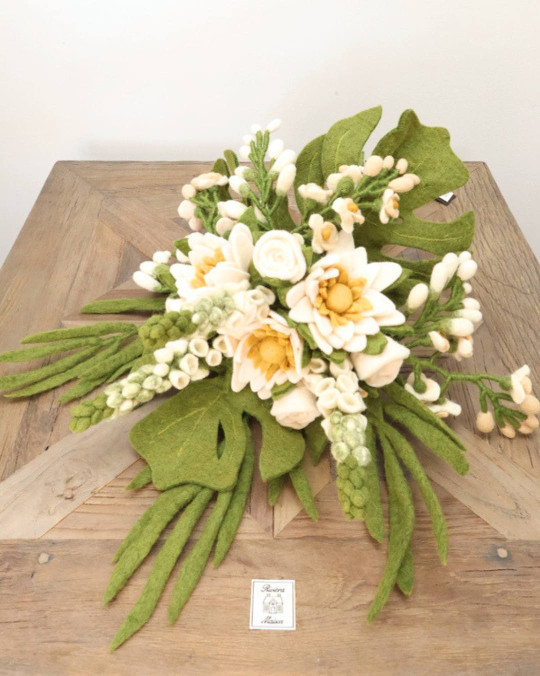 Der Hochzeitsstrauß ist ganz zu sehen und liegt auf einem hellbraunen Tisch . 