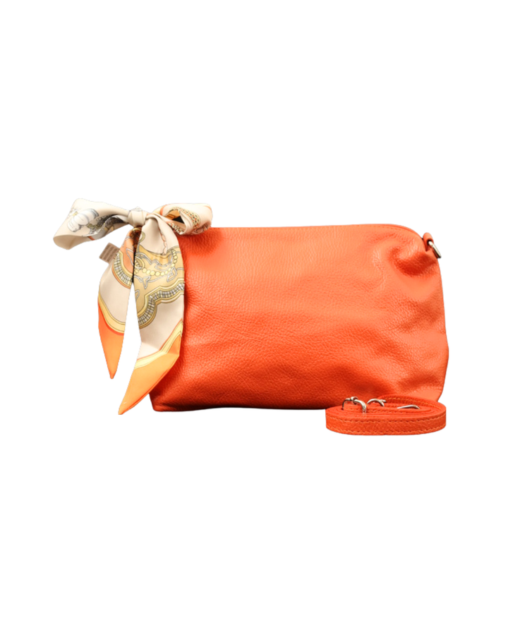 Orangene Leder Handtasche "Brigitte" von Südstrand vor weißen Hintergrund. Am Verschluss hängt ein orange/weißes Tuch. Die Tasche hat einen kräftigen Orange Ton.