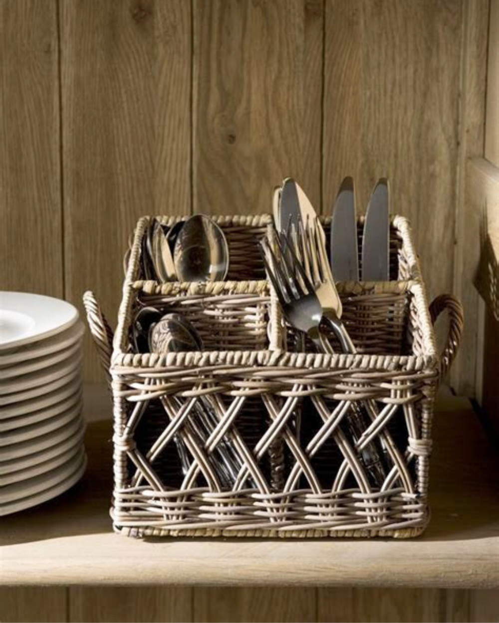 Rattan Korb "Couvert Basket" von Rivièra Maison mit Besteck drinnen in einem Braunen Esszimmerschrank.