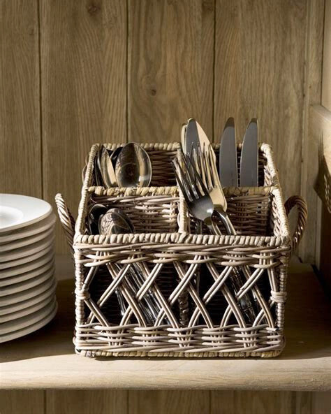 Rattan Korb "Couvert Basket" von Rivièra Maison mit Besteck drinnen in einem Braunen Esszimmerschrank.