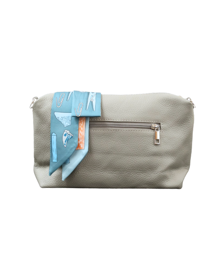 Rückseite der grauen Leder Handtasche "Brigitte" von Südstrand vor weißen Hintergrund. Am Verschluss hängt ein Maritim blaues Tuch.
