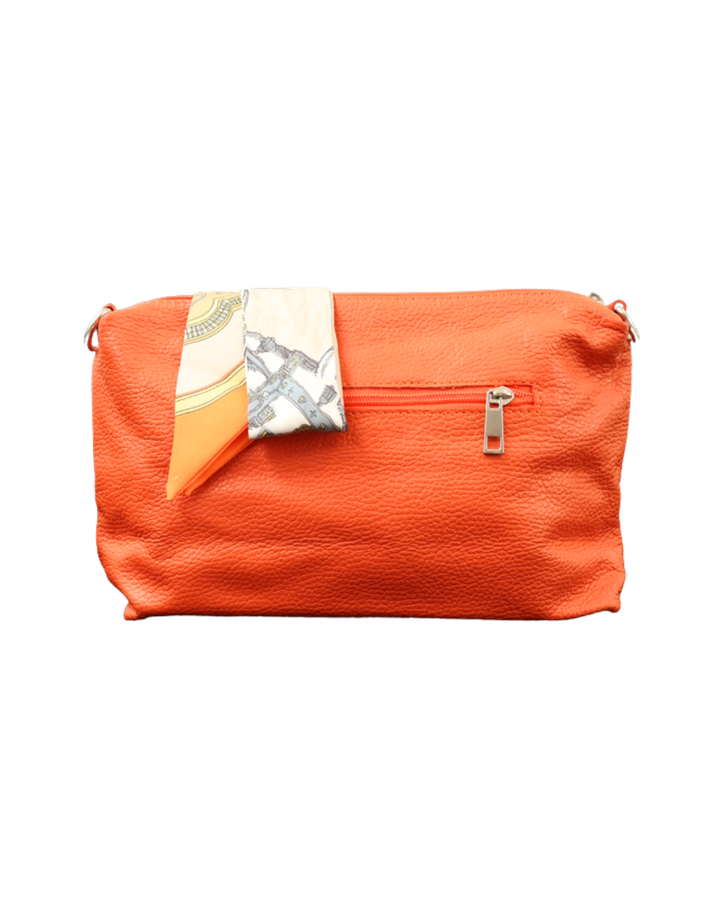 Rückseite der orangenen Leder Handtasche "Brigitte" von Südstrand vor weißen Hintergrund. Am Verschluss hängt ein größtenteils weiß/orangenes Tuch.