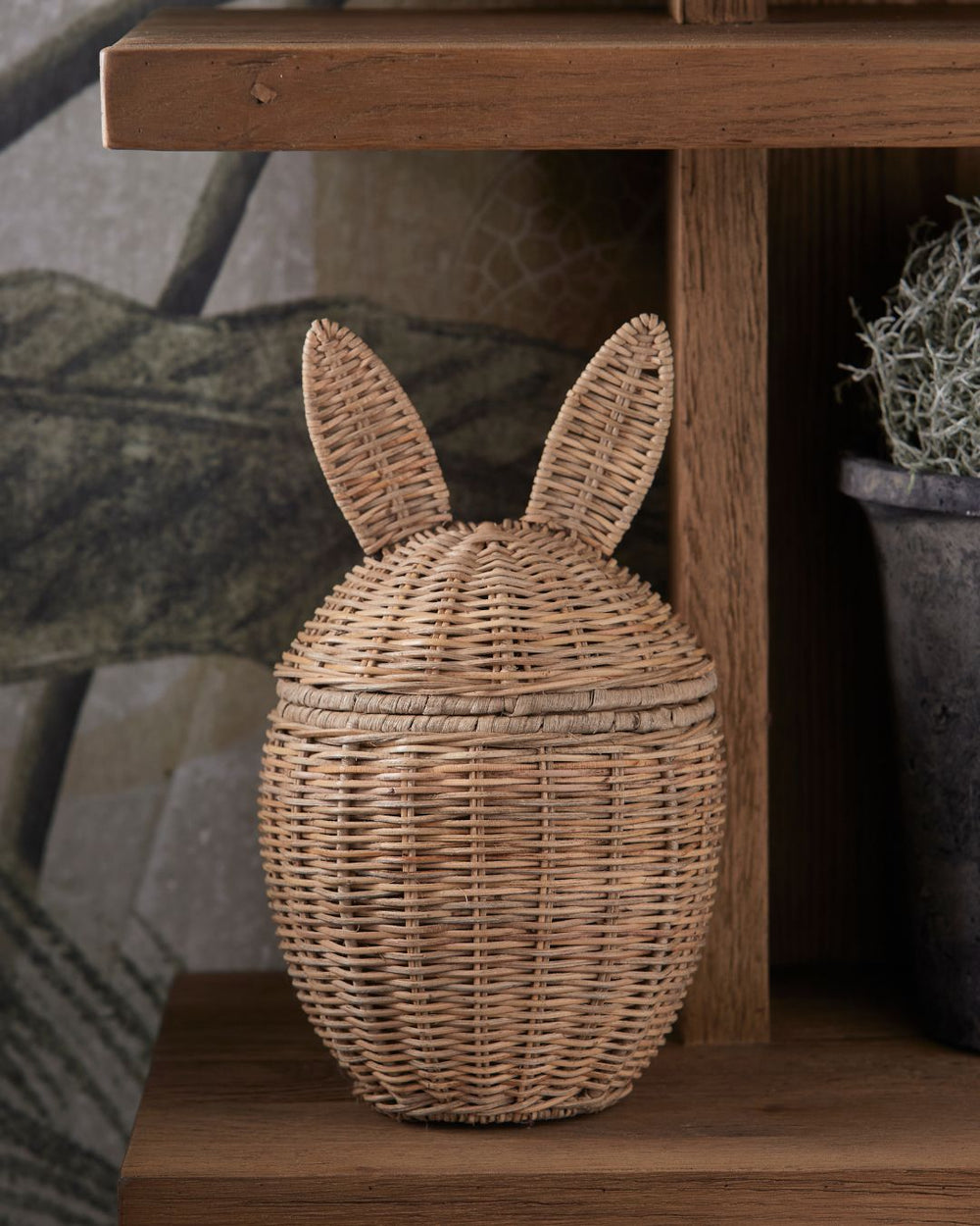 Rustic Rattan Aufbewahrungskorb als Hase von Rivièra Maison dekoriert in einem Holzregal.