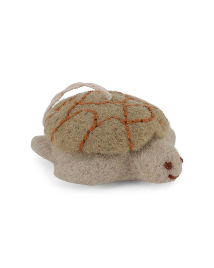 Filzanhänger in Form einer beige-grünlichen Schildkröte von Gry & Sif vor weißem Hintergrund.