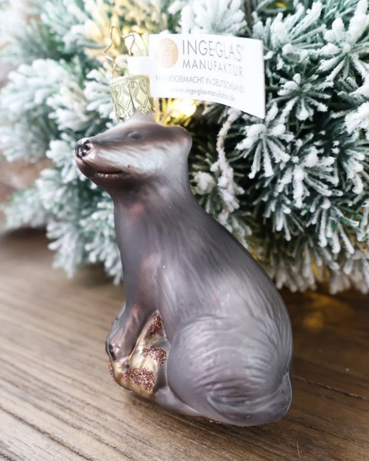 Schräge Ansicht des weihnachtlichen Dachs Ornaments von Inge Glas, welches vor weiß gepudertem Tannengrün auf einem Holztisch dekoriert ist.