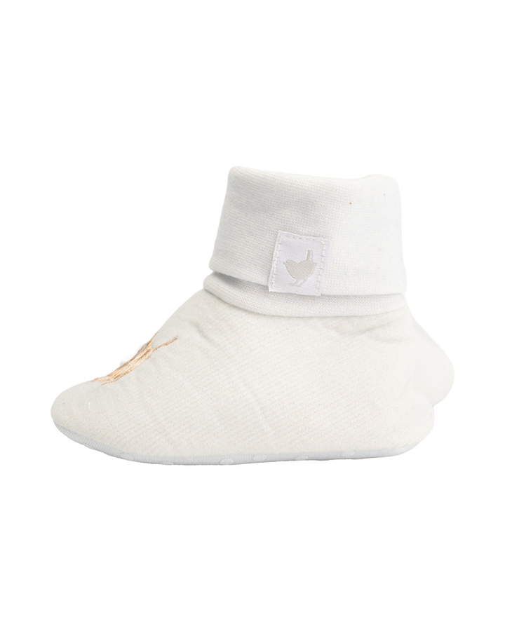 Seitliche Ansicht der weißen Babyschuhe mit umgeschlagenem Bund und dezentem Wrendale-Label.