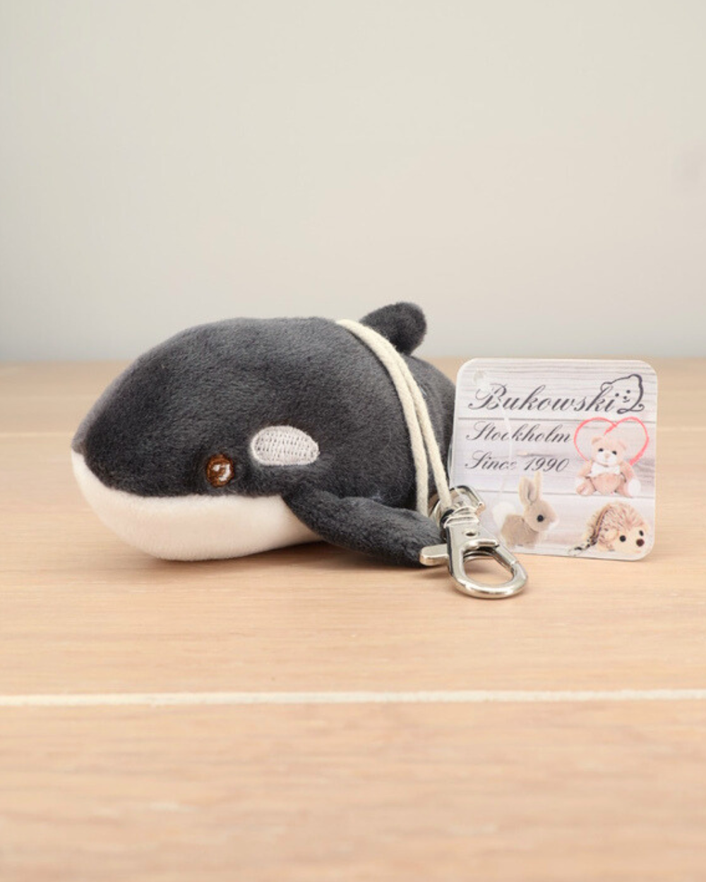 Der Orca Schlüsselanhänger Oreo von Bukowski liegt auf einem Holztisch. Sein weicher Körper und die Flossen sind gut zu erkennen.