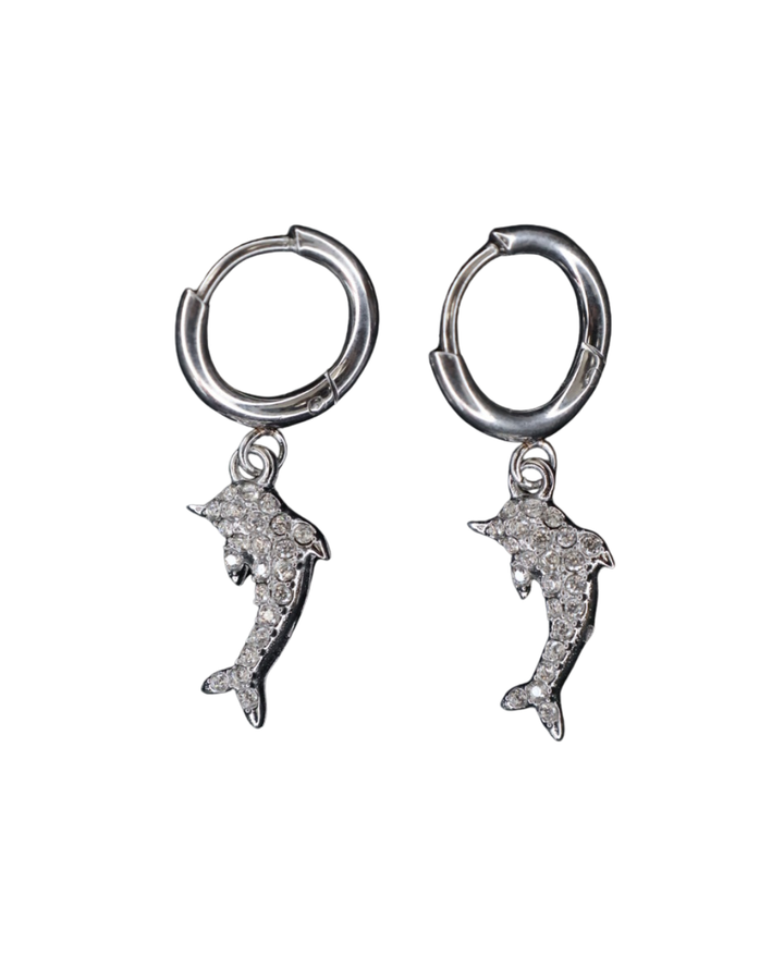 Silberne Delfin-Ohrringe von Dottilove verziert mit verschiedenen Glitzersteinen auf weißen Hintergrund.