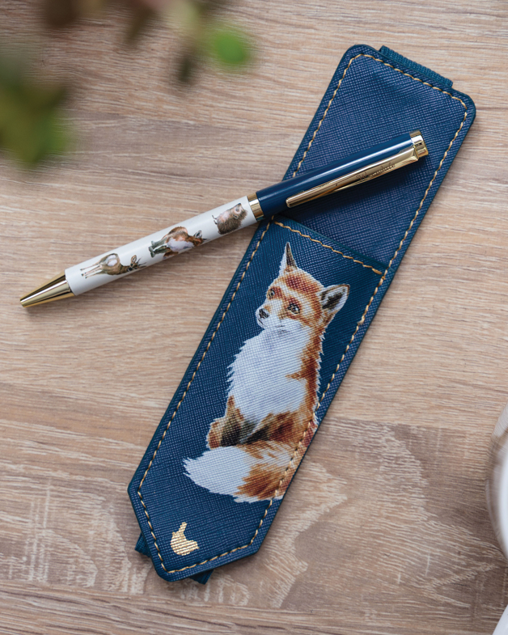Kugelschreiber und blaues Stiftetui mit Fuchsmotiv von Wrendale Designs, dekoriert auf einem Holztisch.