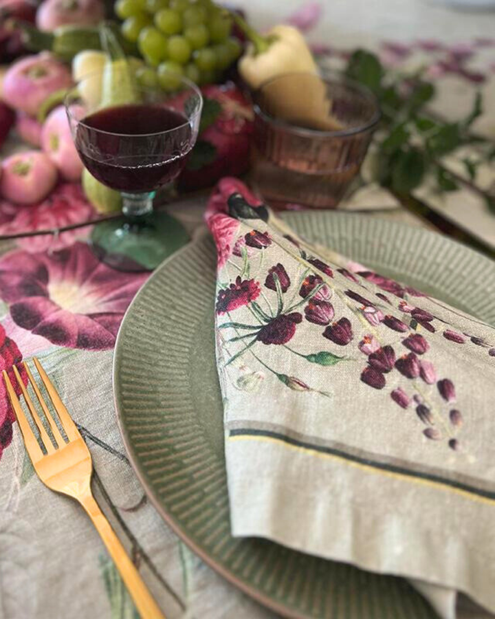 Detailansicht des Blumenmusters der Leinenserviette Blossom Garden von Koustrup & Co. auf hellem Grund, mit üppigen Blumen und Blättern in Rosa und Grün.