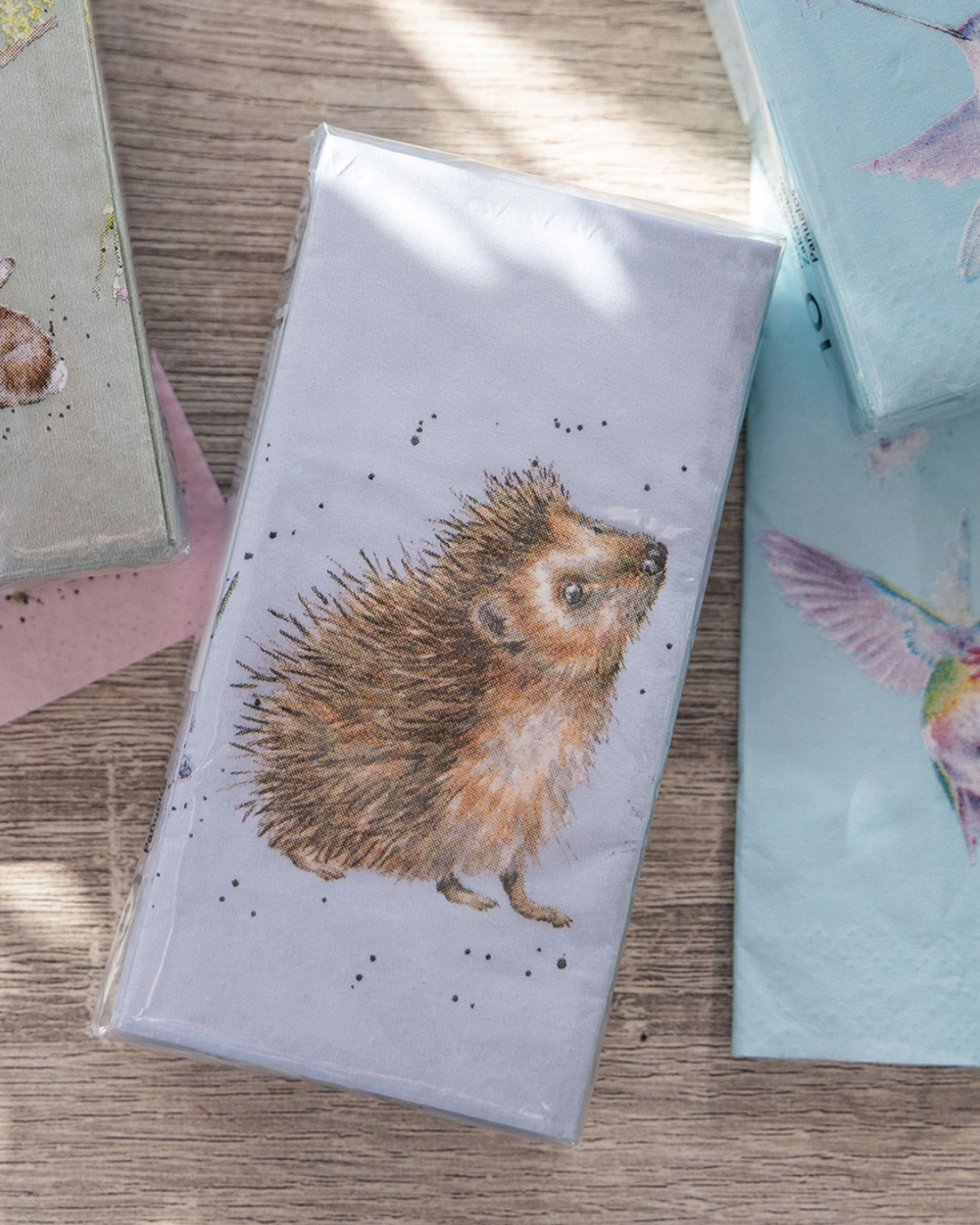 Ein Päckchen Igel Taschentücher von Wrendale Designs mit Motiv von Hannah Dale liegt auf einem Holztisch, daneben weitere Taschentücher mit Tiermotiven