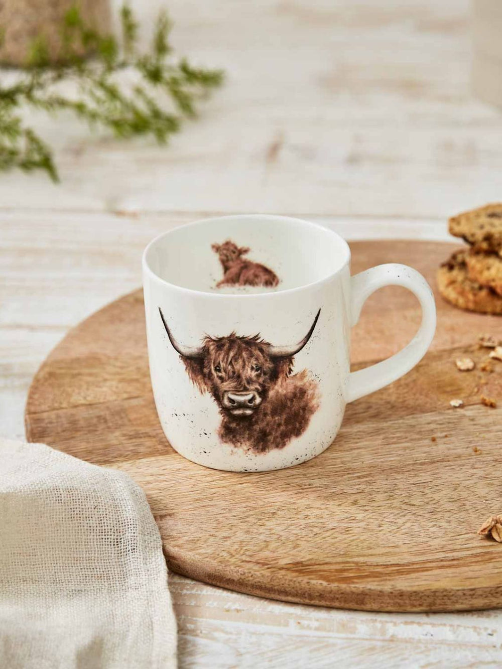 Tasse mit Highland Kuh Motiv dekoriert auf einem Tisch von Wrendale Designs.