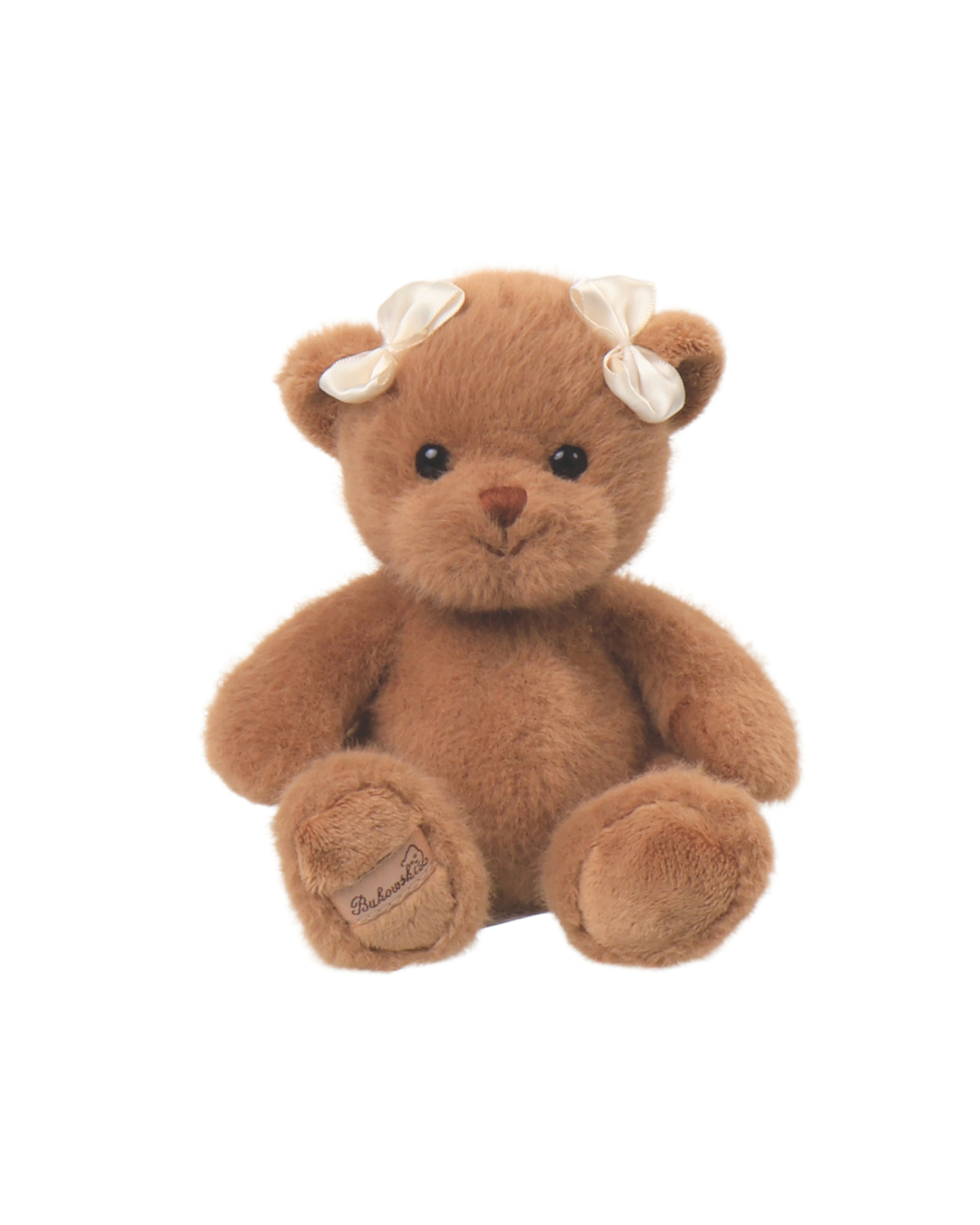 Ein brauner Teddybär von Bukowski mit weißer Schleife im Haar sitzt auf weißem Hintergrund.