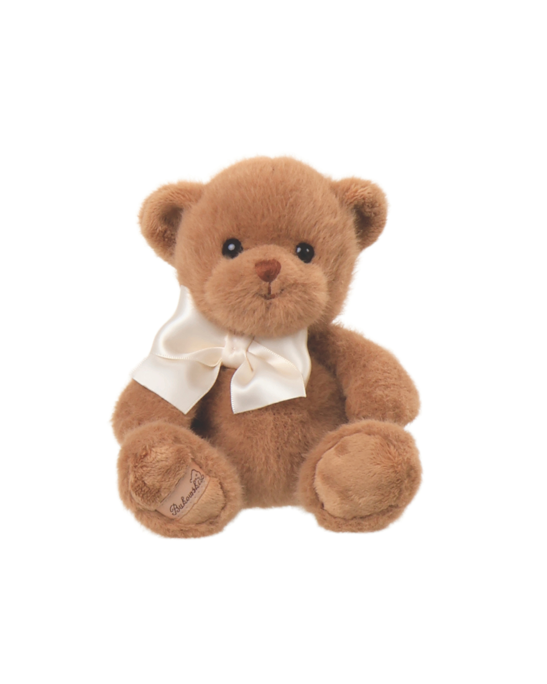 Ein brauner Teddybär von Bukowski mit cremefarbener Fliege sitzt auf weißem Hintergrund.