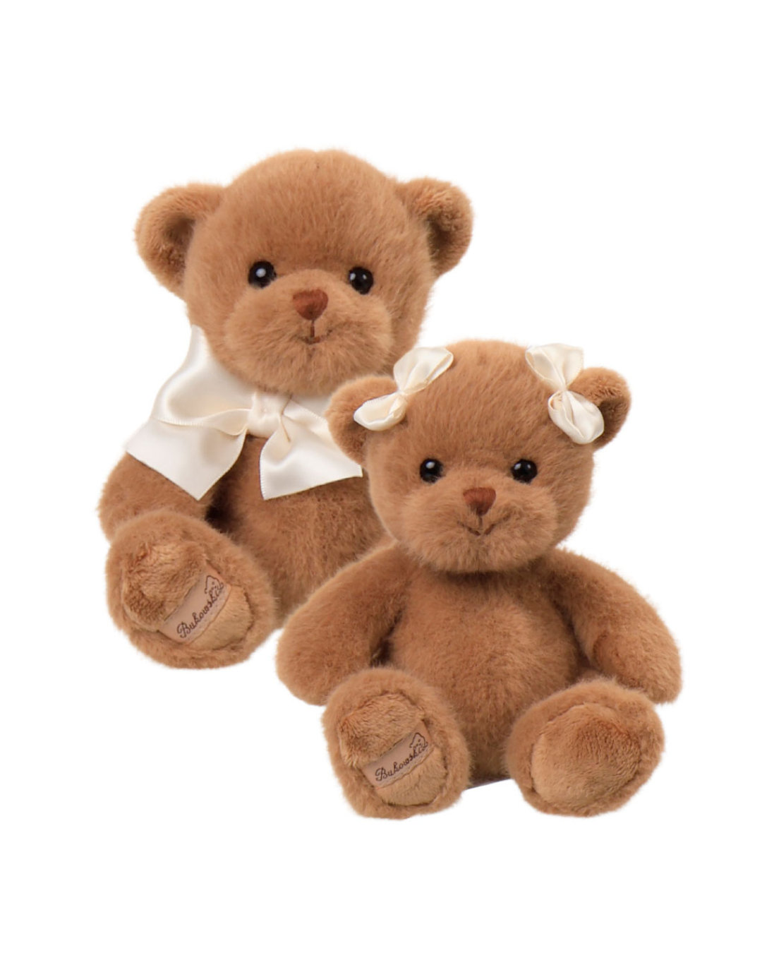 Zwei braune Teddybären von Bukowski sitzen nebeneinander auf weißem Hintergrund. Ein Bär trägt eine cremefarbene Fliege, der andere eine weiße Schleife im Haar.