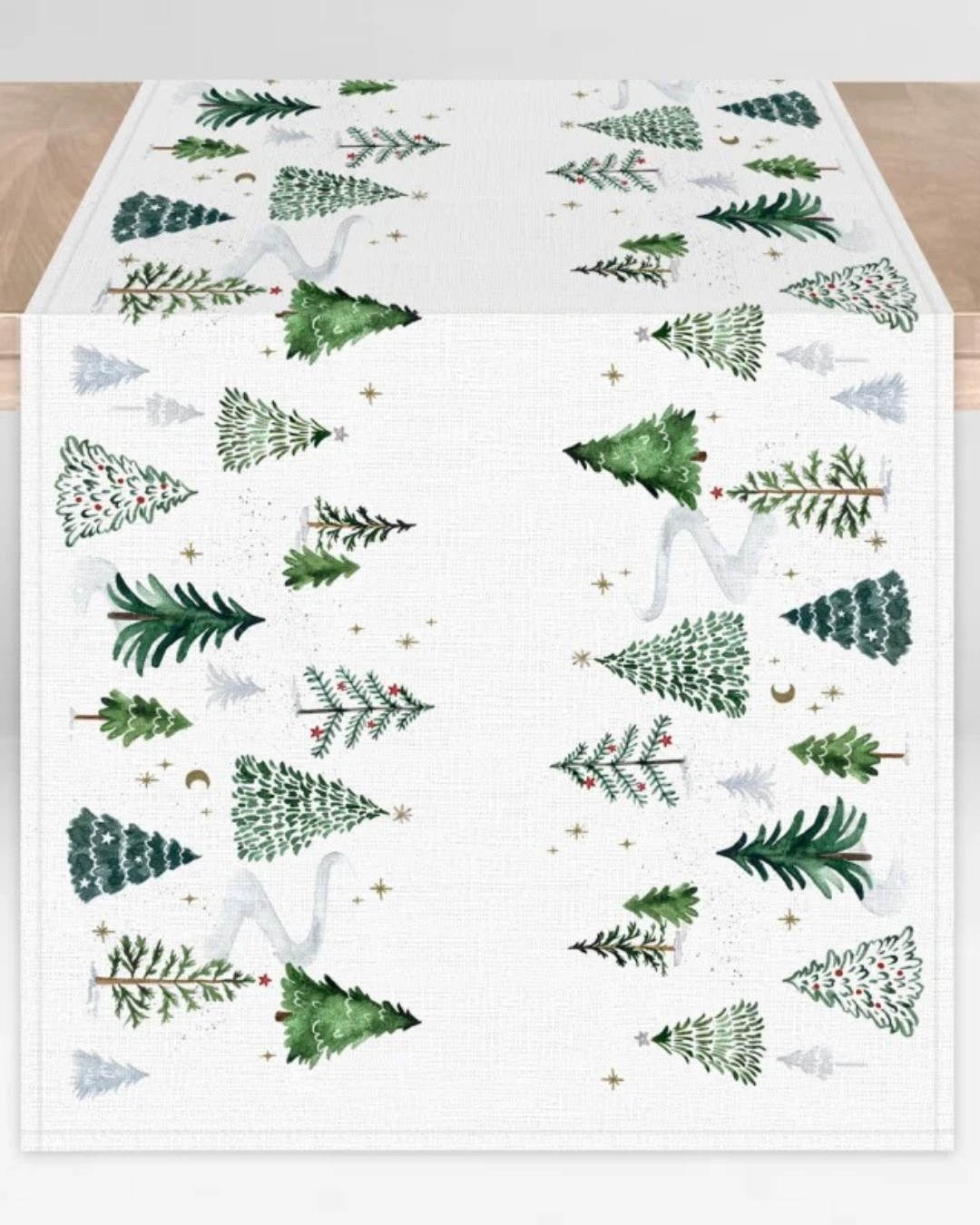 Tischläufer Wintertannen vom Grätz Verlag. Illustriert von Anna Inspira sind Tannenbäume, winterliche Landschaft und goldene Highlights zu sehen. Hier liegt der Tischläufer ausgefaltet auf einem Tisch.