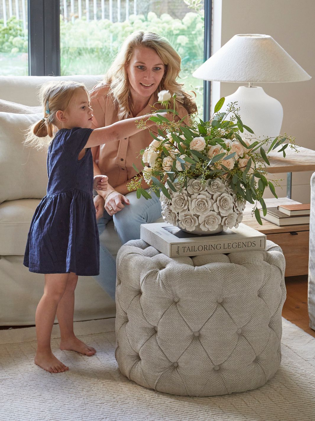 Eine Mutter dekoriert mit ihrer Tocher die Blumenvase mit den Keramikrosen von Rivièra Maison.