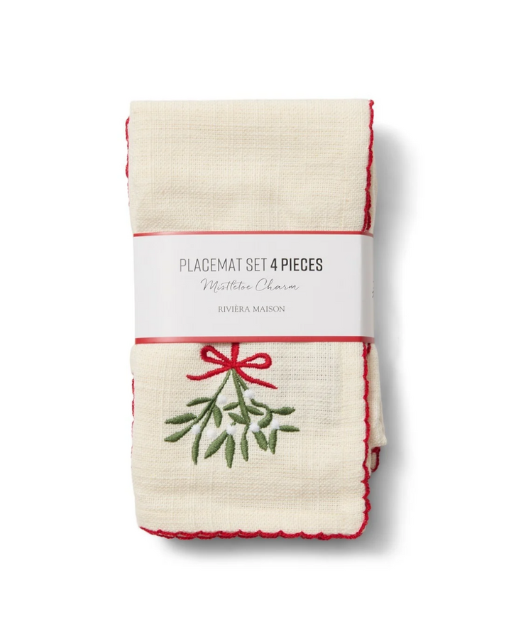 4er Set Platzsets "Mistletoe Charm" von Riviera Maison noch verpackt vor weißen Hintergrund. Das Platzset ist größtenteils beige/weiß mit einem roten Rand und einem Mistelzweig als Motiv.