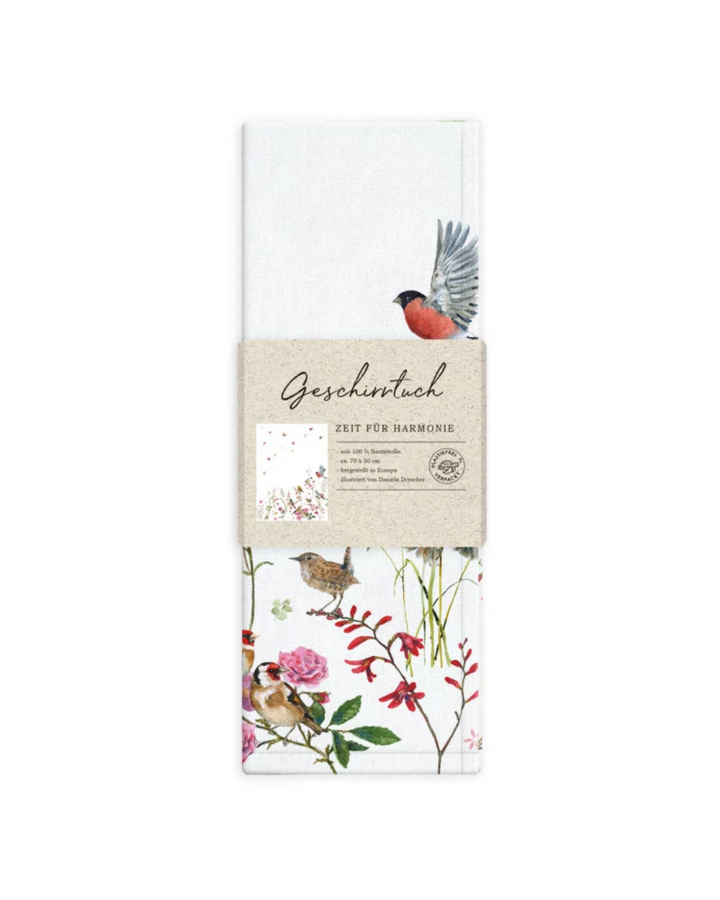 Verpackung des Geschirrtuchs Zeit für Harmonie vom Grätz Verlag – Illustration von Daniela Drescher mit Vogel im Flug, Wiese & Blumen.