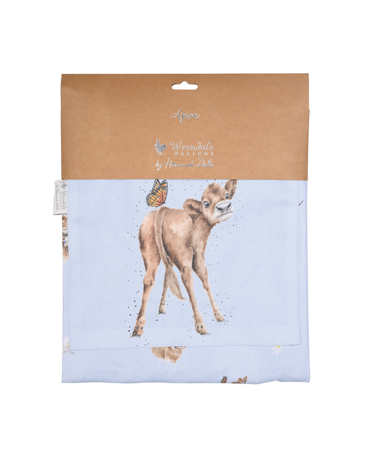 Hell blaue Kuh-Kochschürze von Wendale Designs noch verpackt vor weißen Hintergrund. Das Motiv ist eine junge Kuh, welche von hinten zu sehen ist, sich jedoch zur Kamera dreht. Auf ihr sitzt außerdem ein Schmetterling.