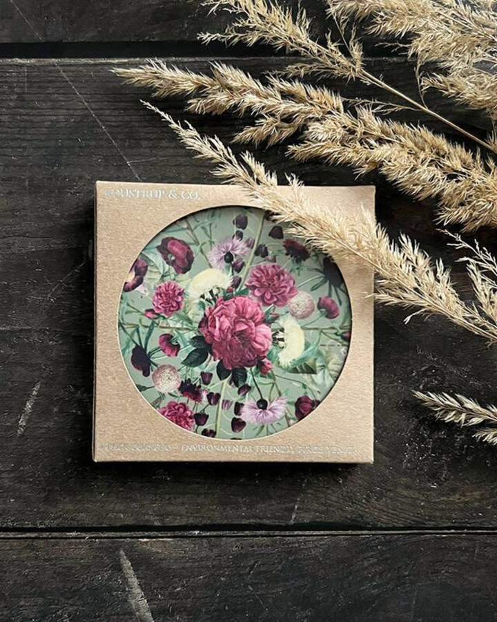 Untersetzer "Blossom Garden" von Koustrup & co mit abstrakten Blumen Motiv verpackt auf dunklen Holztisch.